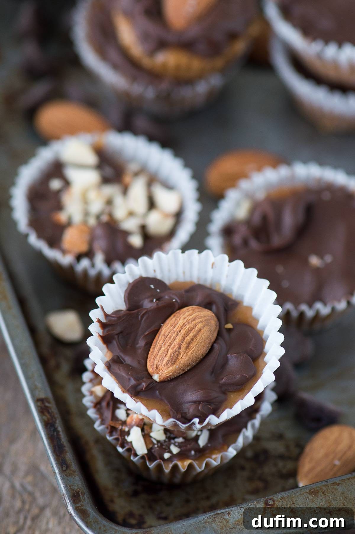 Freshly made golden toffee bites cooling on a metal baking tray, some topped with melted chocolate and almonds, awaiting their final set.