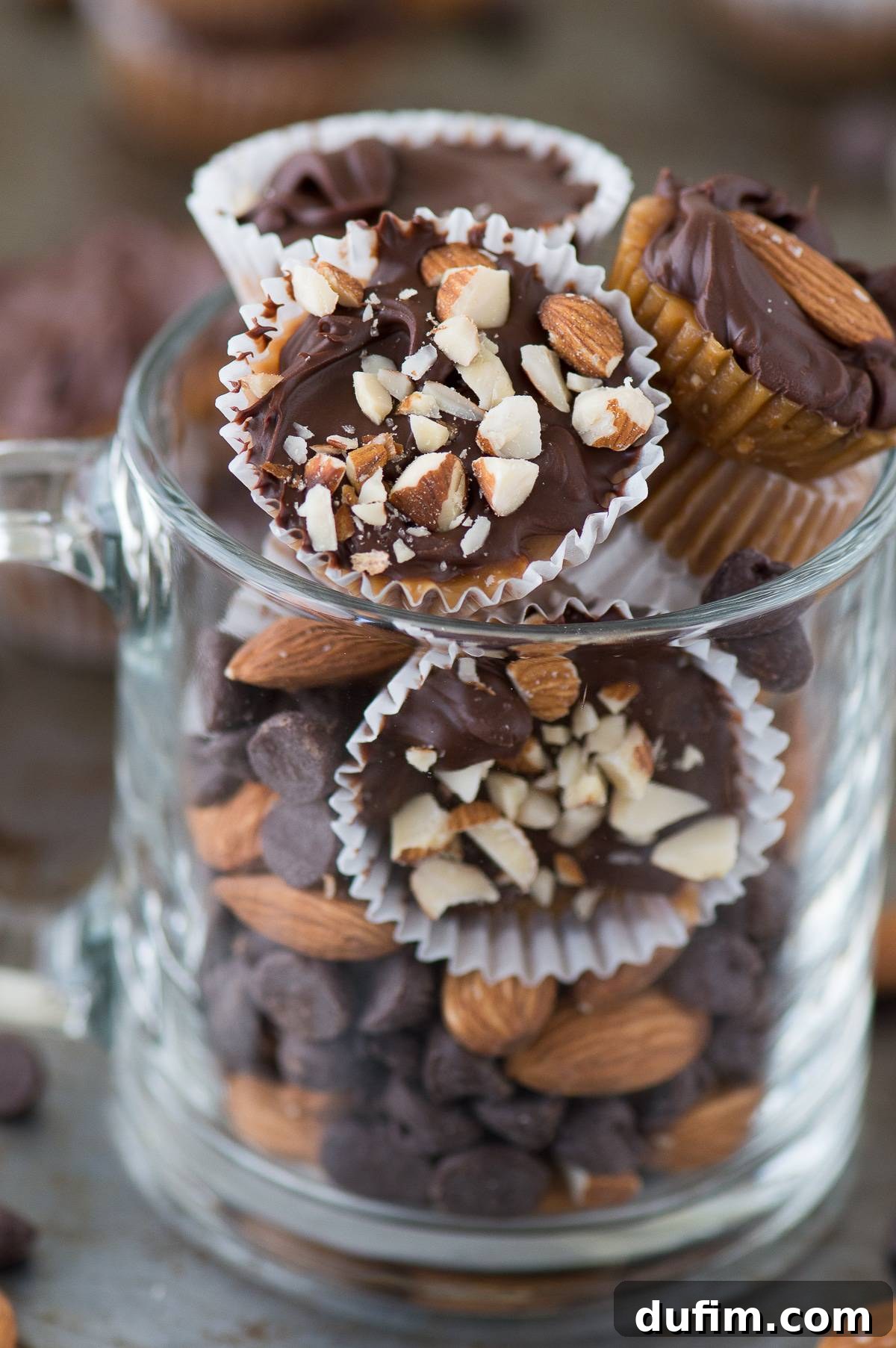 A charming glass mug filled to the brim with various homemade almond toffee bites, showcasing their individual perfection and diverse toppings.