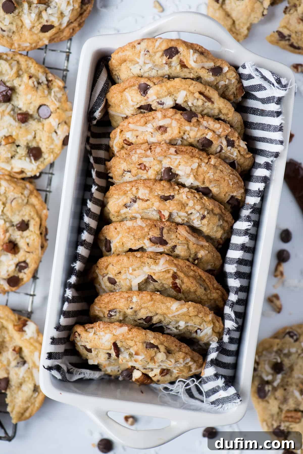 Freshly baked Cowboy Cookies neatly lined up in a white loaf pan, showcasing their golden-brown edges and generous mix-ins.