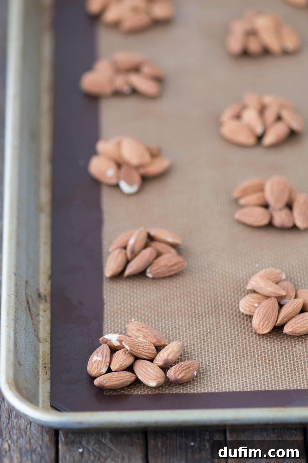 Williams Sonoma's Iconic Sticky Paws, Perfected at Home 3 Carefully arranged almond clusters on a silicone baking mat, ready for caramel.