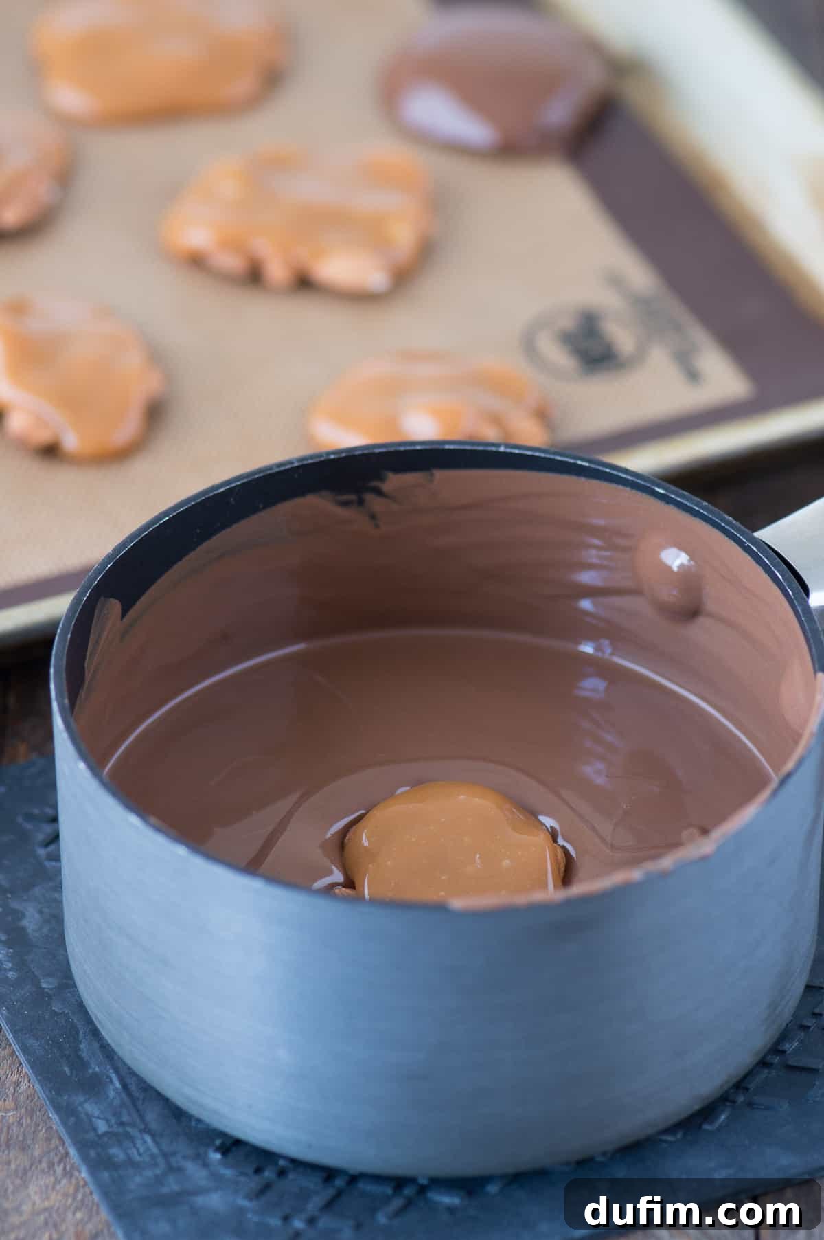 Williams Sonoma's Iconic Sticky Paws, Perfected at Home 6 A Sticky Paw cluster being carefully dipped into a bowl of melted chocolate with a fork, showing the hands-on process.