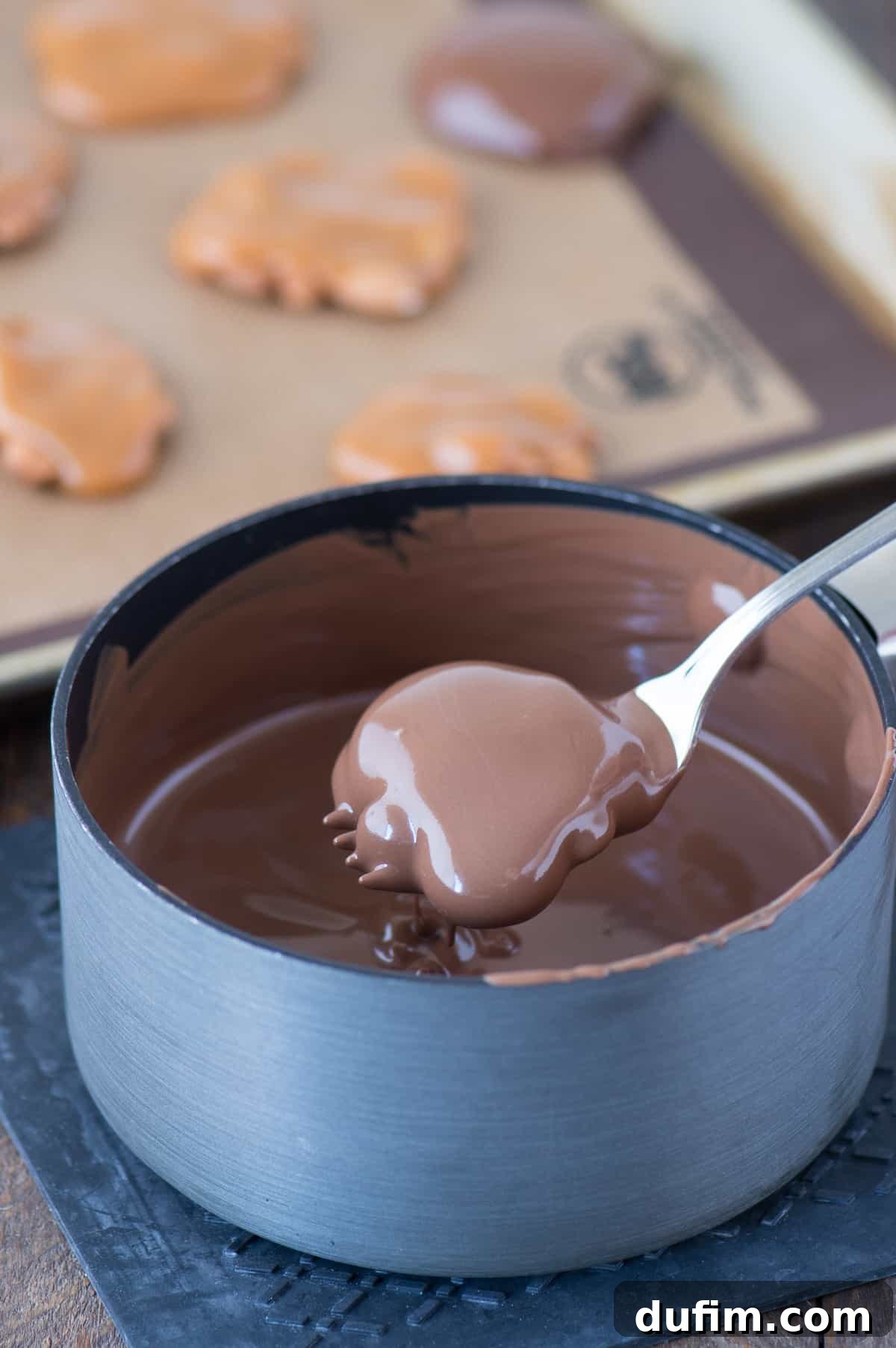 Williams Sonoma's Iconic Sticky Paws, Perfected at Home 7 Another image of a Sticky Paw being dipped in chocolate, demonstrating the dipping technique.