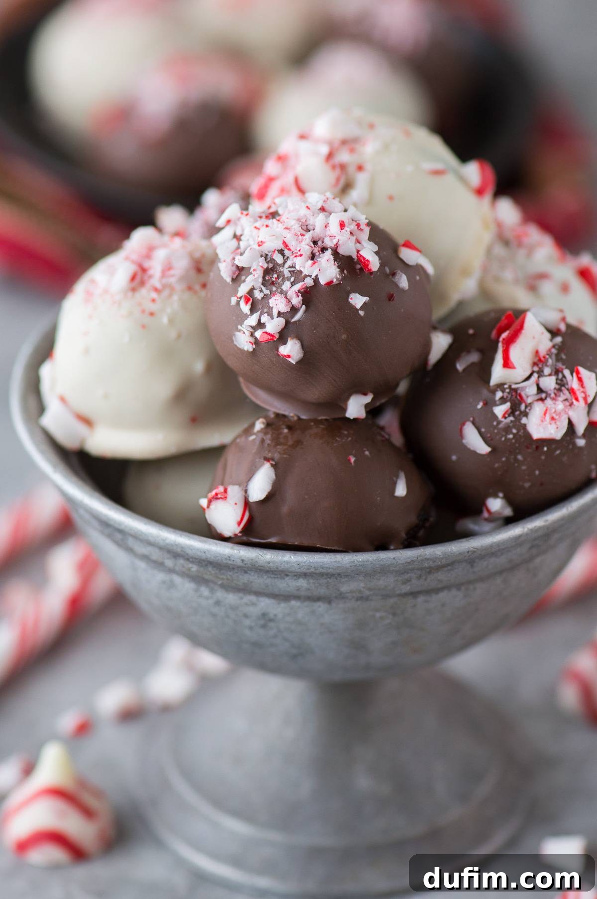 A metal bowl brimming with a generous assortment of chocolate and white chocolate Peppermint Oreo Balls, some dusted with crushed candy canes.