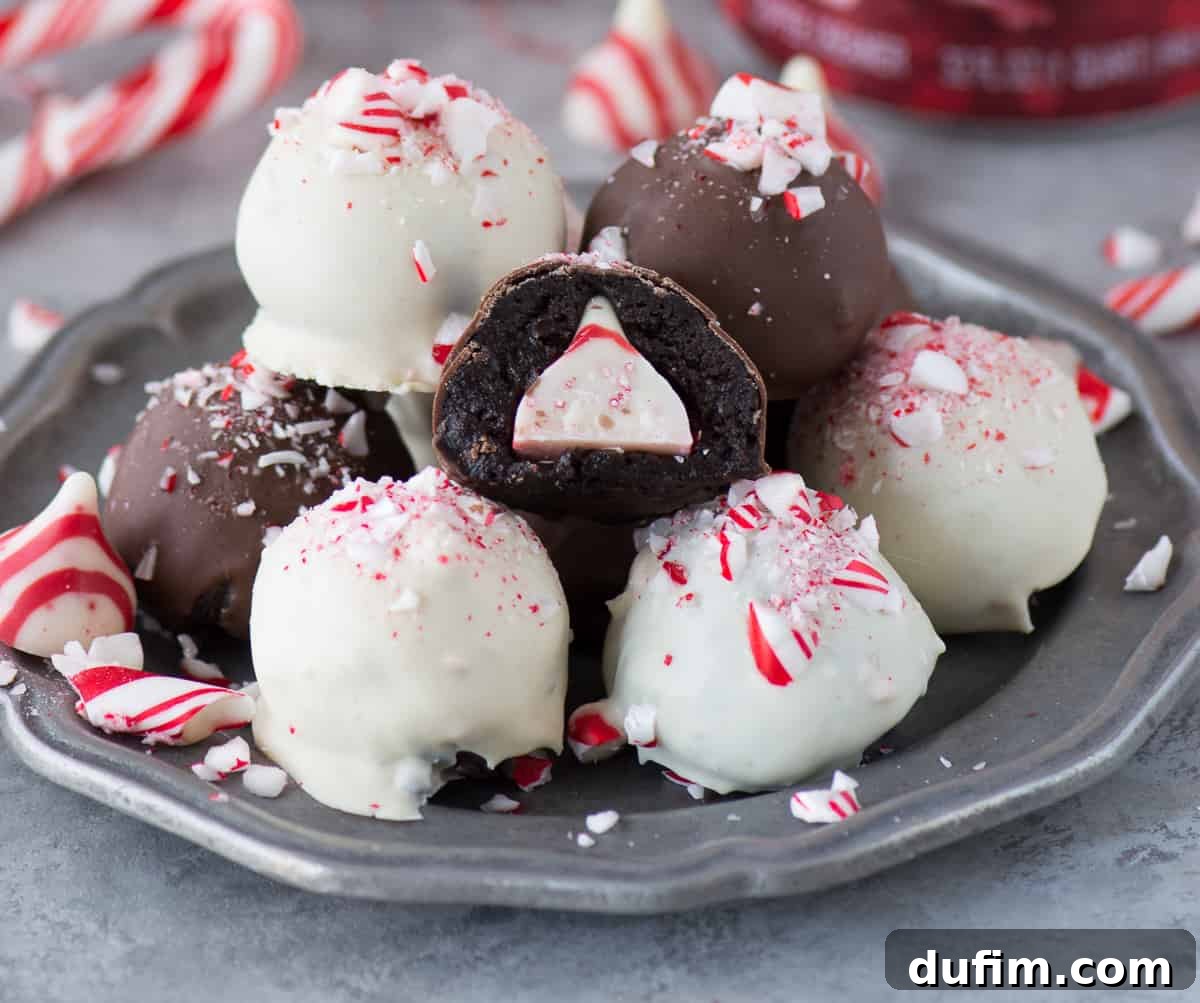 A vibrant display of freshly dipped chocolate and white chocolate Peppermint Oreo Balls, adorned with festive crushed candy canes, nestled in a metal bowl.