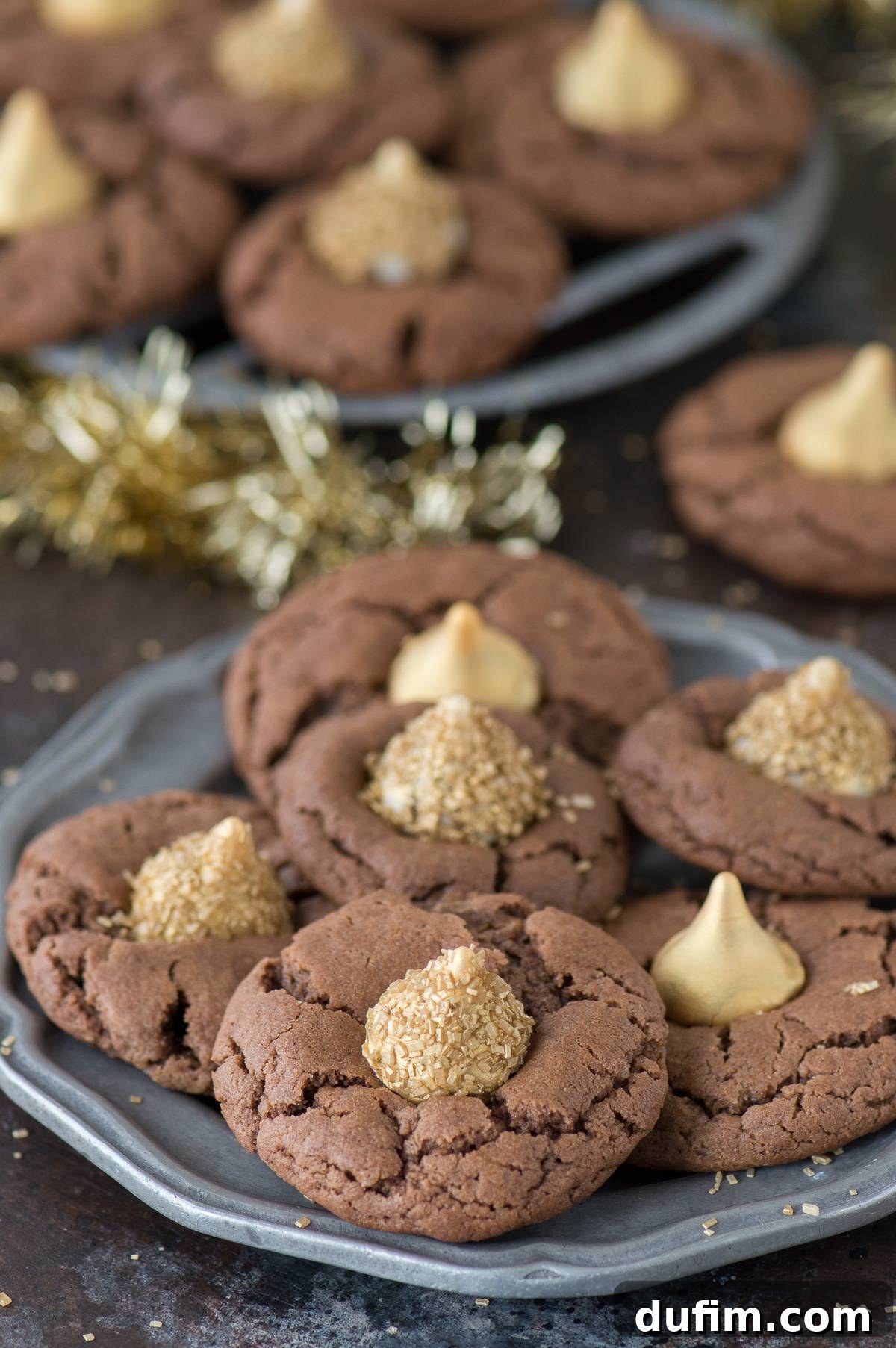 Close-up of Midnight Kiss Cookies on a metal plate, showing the intricate gold dusting on the Hershey's Kisses and the delicious chocolate cookie texture.