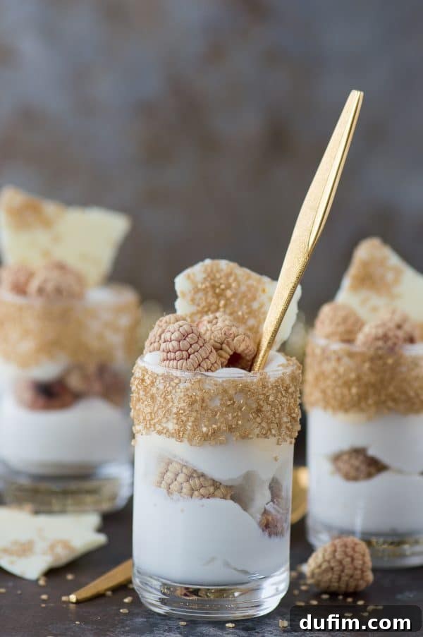Decadent White Chocolate Raspberry Mousse 3 Close-up of the elegant white chocolate raspberry mousse dessert with gold-rimmed glass and gold-sprayed raspberries, highlighting its festive appeal.
