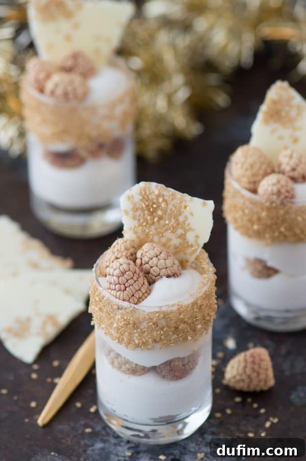 Decadent White Chocolate Raspberry Mousse 4 Three individual serving glasses of white chocolate raspberry mousse, showcasing the golden rims and fresh raspberry garnish.