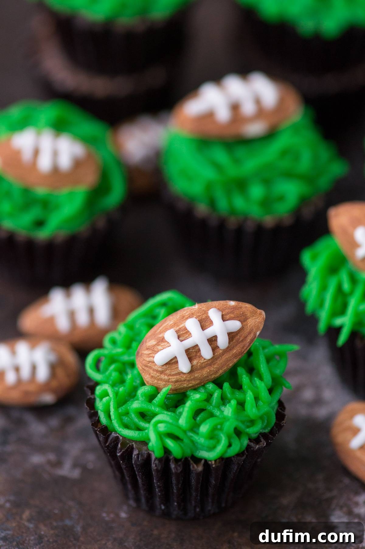 Touchdown Treats Reese Peanut Butter Cups 2 Delicious Reese's Peanut Butter Football Cups topped with vibrant green frosting and almond footballs, perfectly arranged for a game day party.