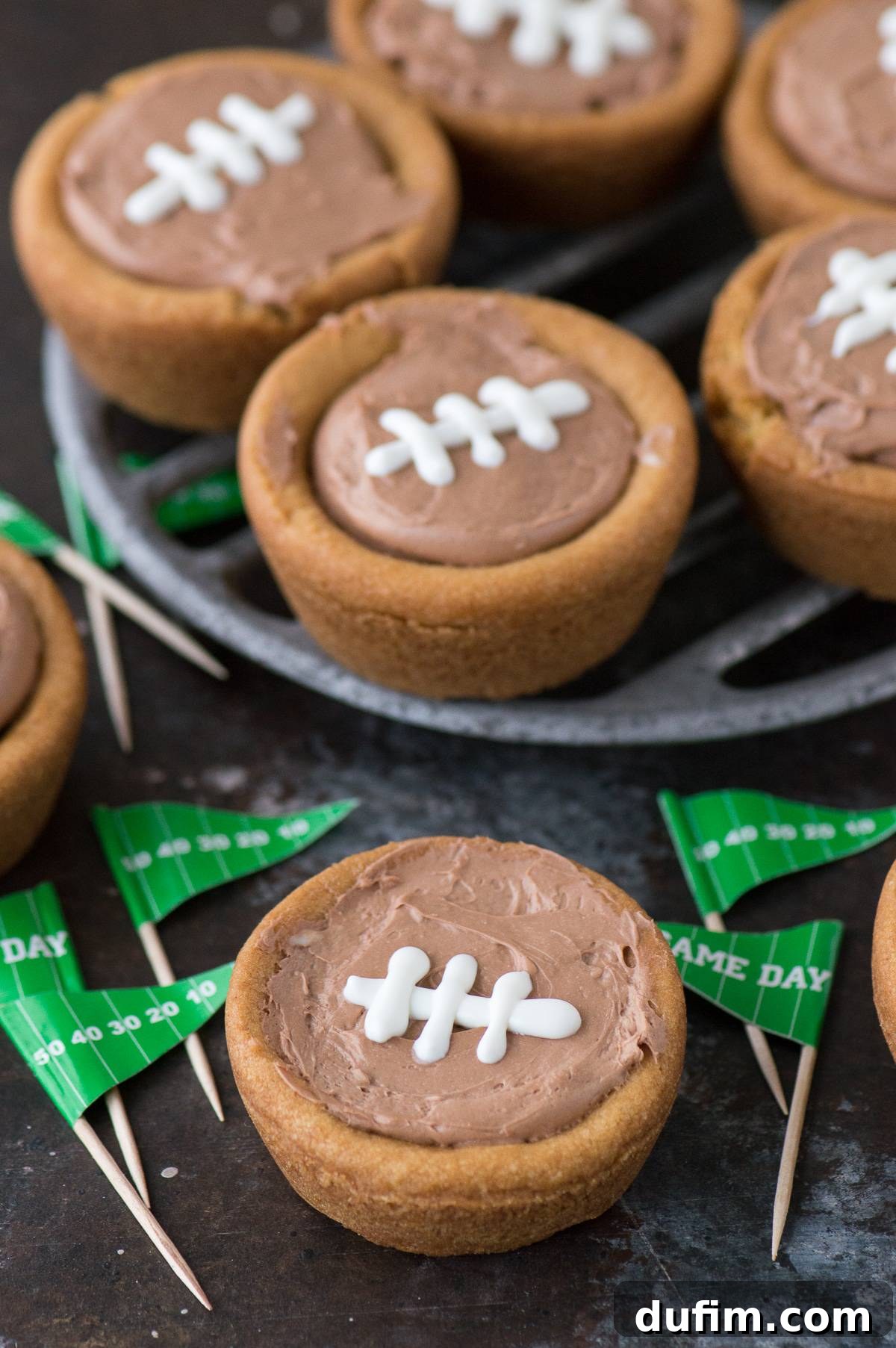 A serving plate filled with delicious cheesecake sugar cookie football cups, perfectly decorated for a game day party