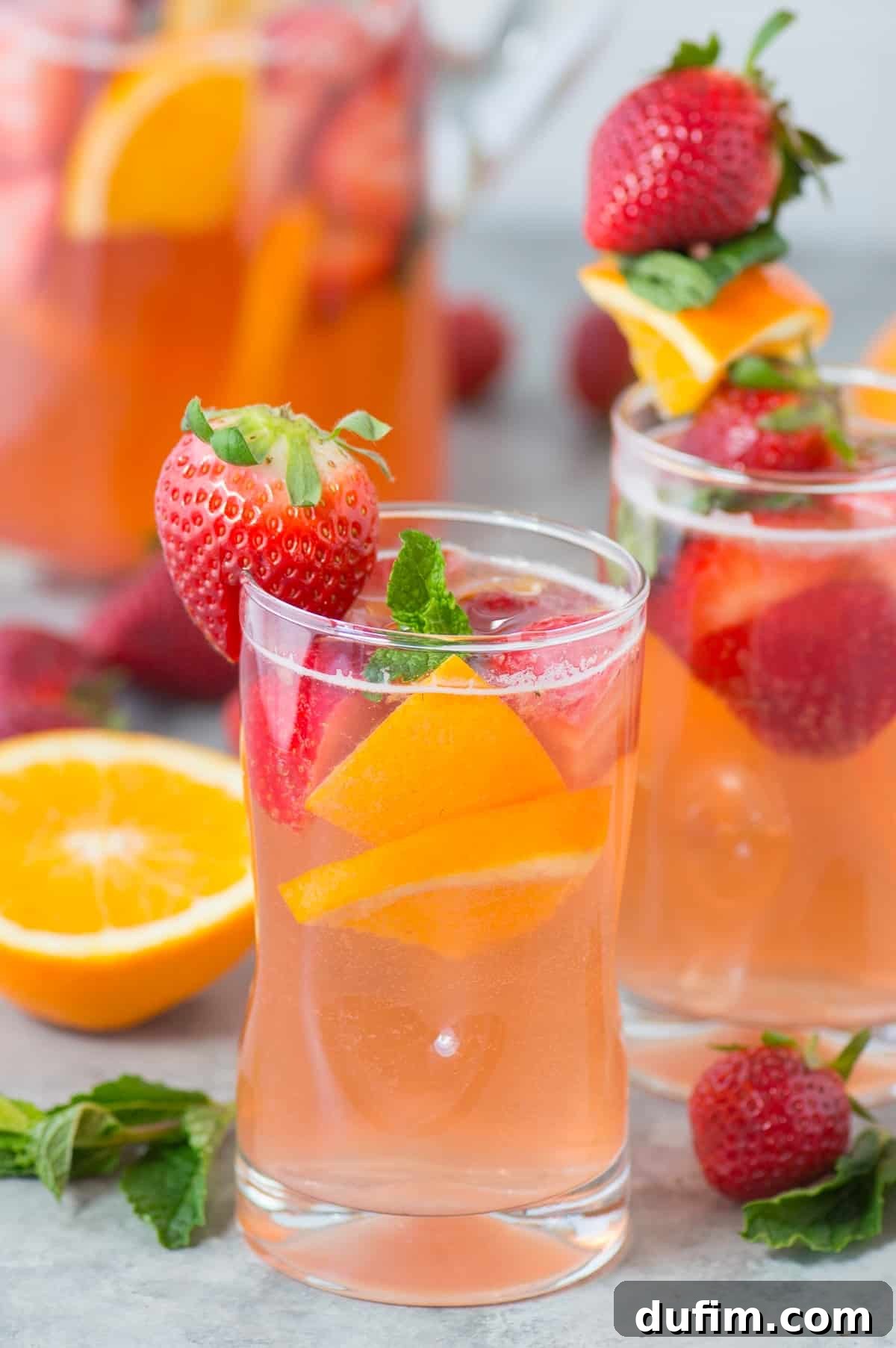A single glass of homemade strawberry sangria, garnished with fresh strawberries, orange slices, and mint leaves, glowing invitingly.