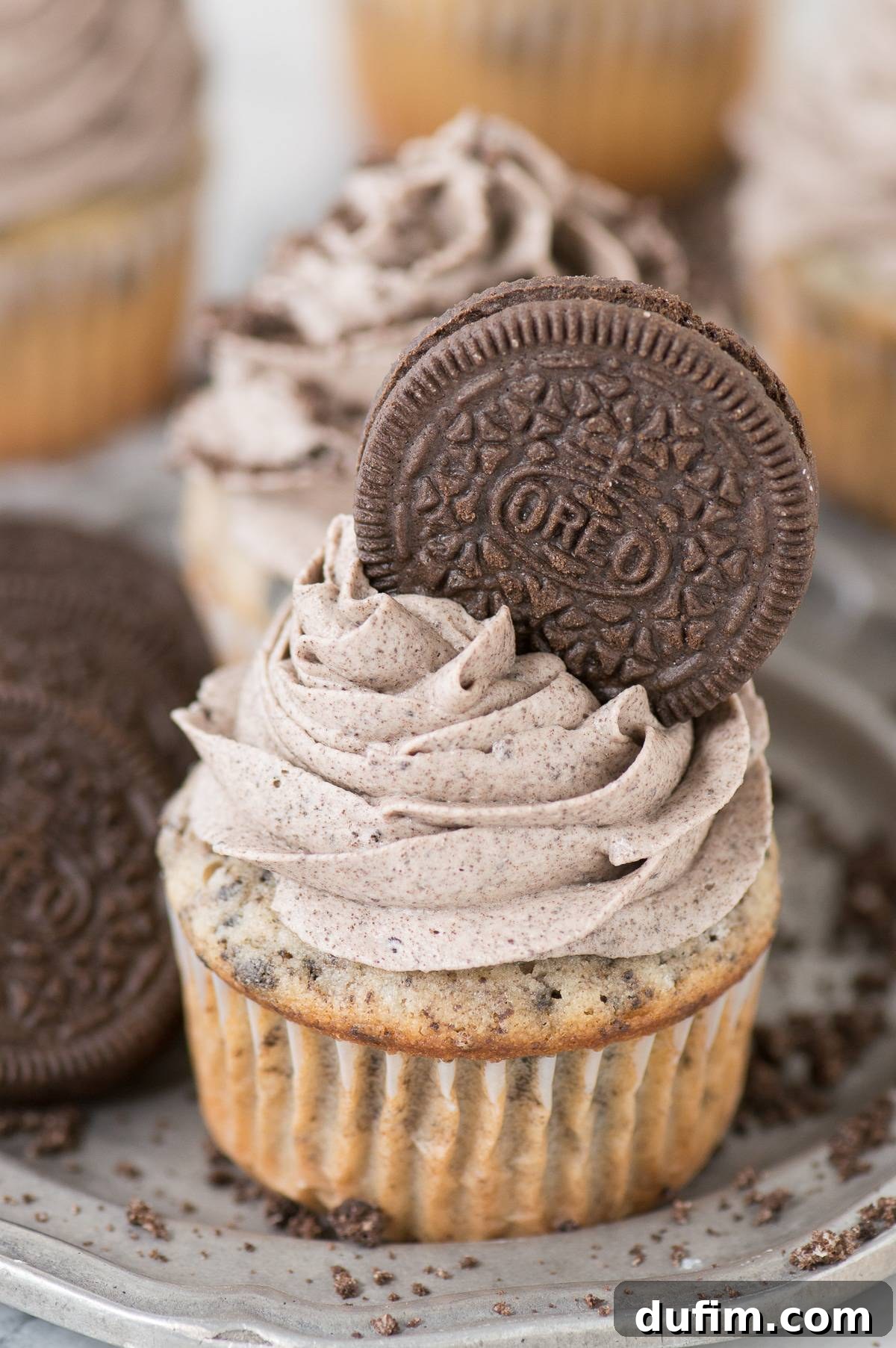 Decadent Oreo cupcake topped with a swirl of rich Oreo frosting and a whole Oreo cookie on a metal plate, ready to be enjoyed.