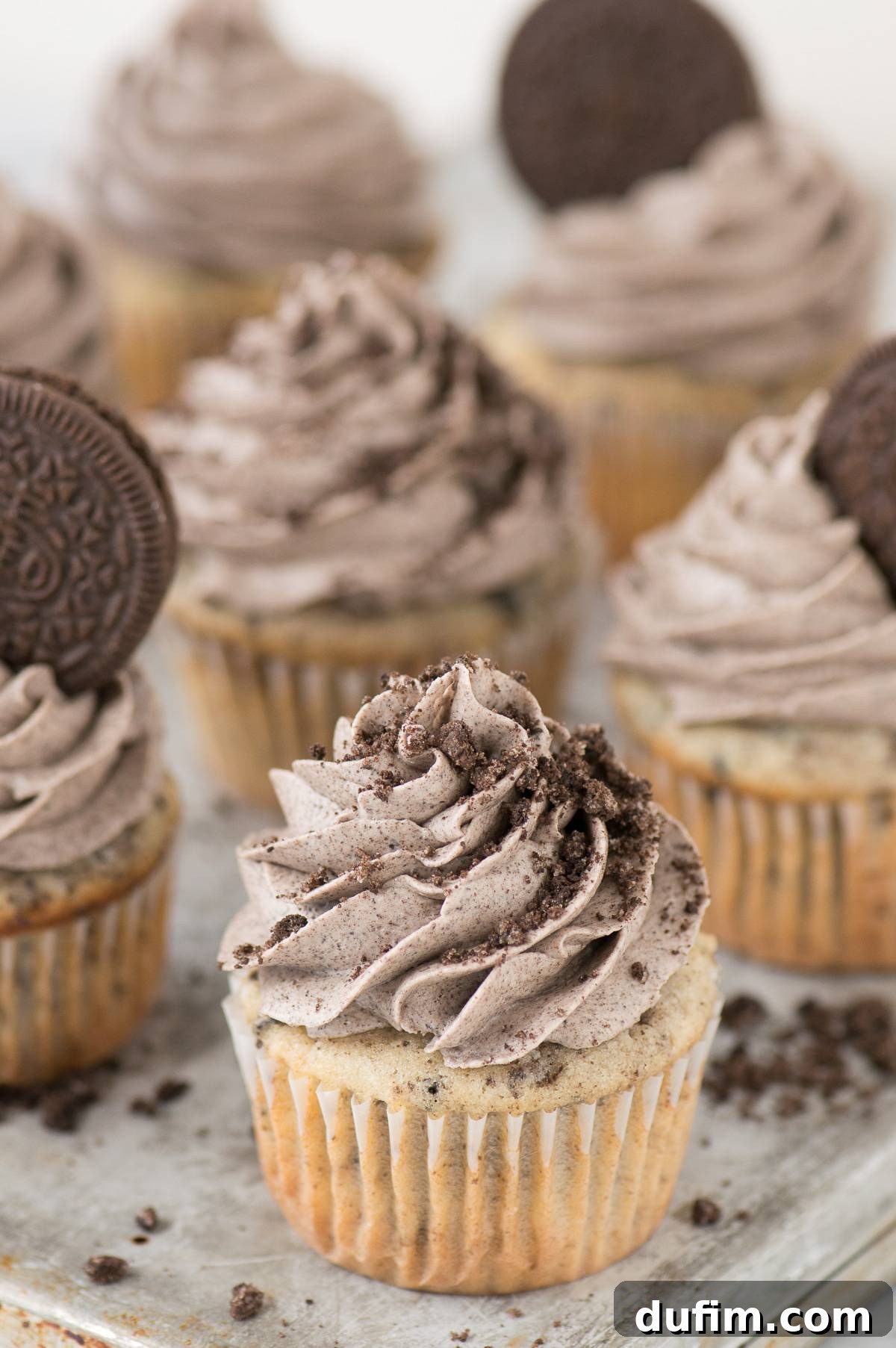 A freshly baked cookies and cream cupcake with a perfect swirl of Oreo frosting, ready to be served, on a metal baking sheet.