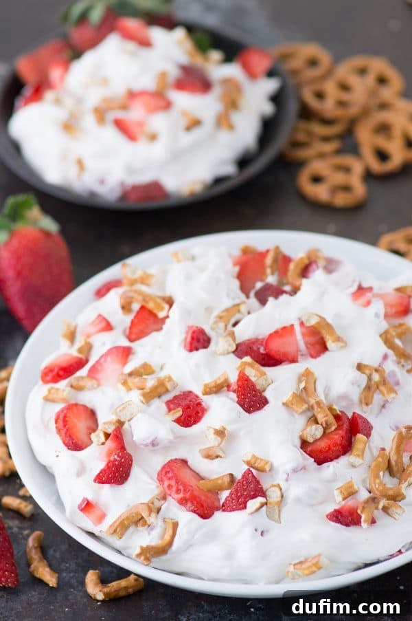 A vibrant bowl of Strawberry Pretzel Fluff Salad with fresh strawberries and crushed pretzels on top, ready for a summer picnic.