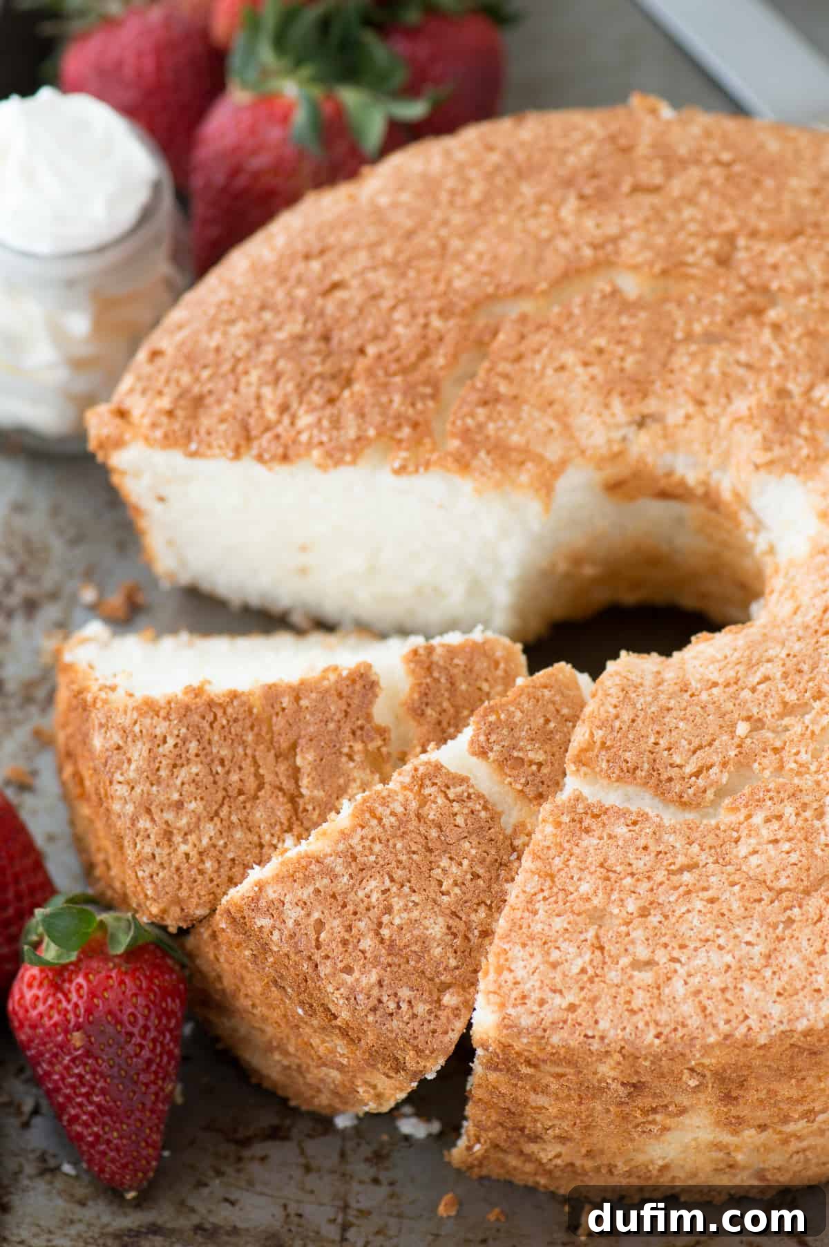 Heavenly Homemade Angel Food Cake 2 A beautifully golden-brown, homemade angel food cake with a light and airy texture, presented on a white plate with fresh berries. This is the ultimate recipe for a fluffy and delicate angel food cake, easily adaptable for gluten-free diets.