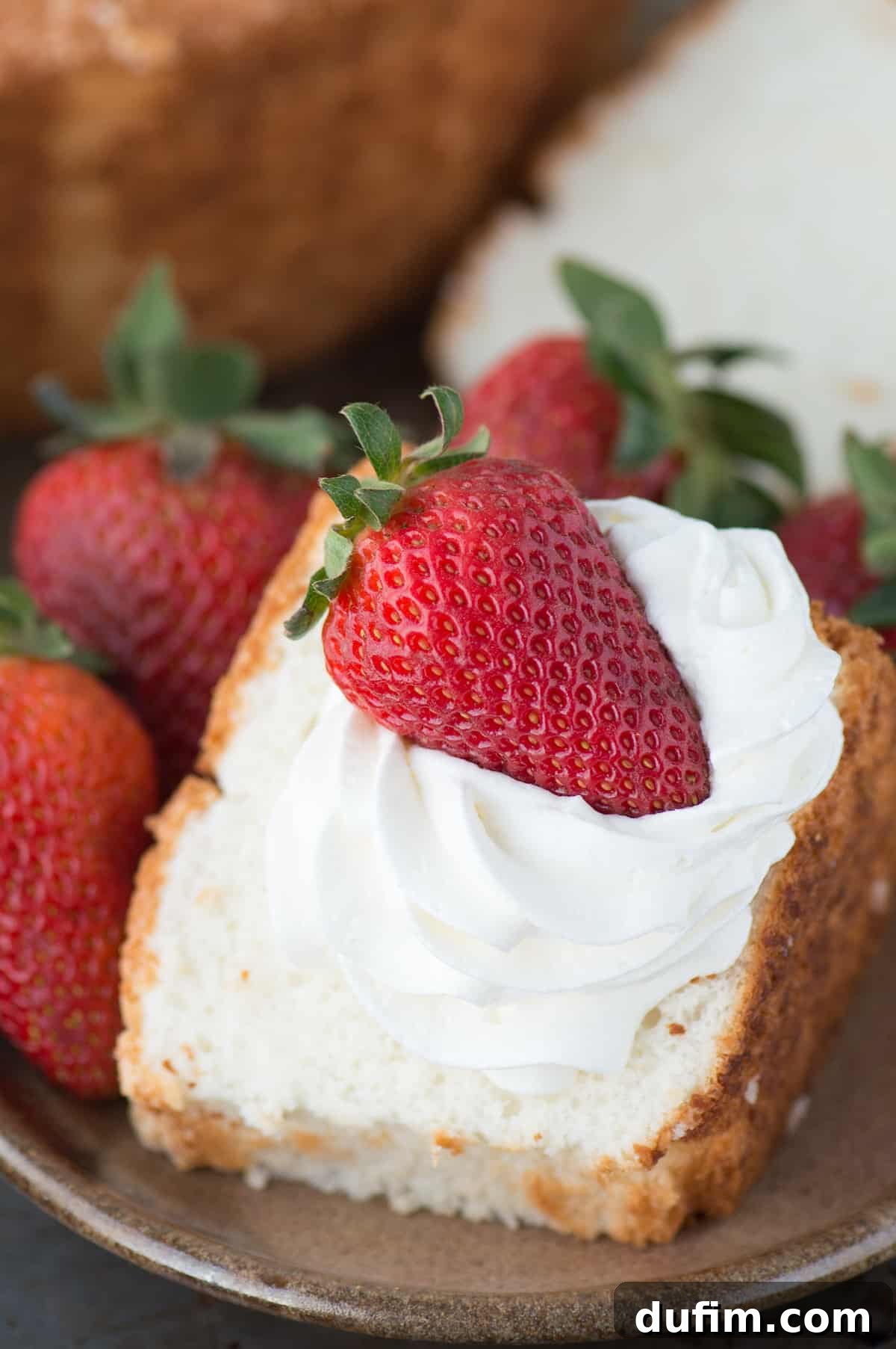Heavenly Homemade Angel Food Cake 6 A vibrant display of a homemade angel food cake slice topped with a generous swirl of whipped cream and a handful of fresh mixed berries, emphasizing its inviting appearance and delightful taste. This versatile recipe, perfect with all-purpose or gluten-free flour, is ideal for any occasion.
