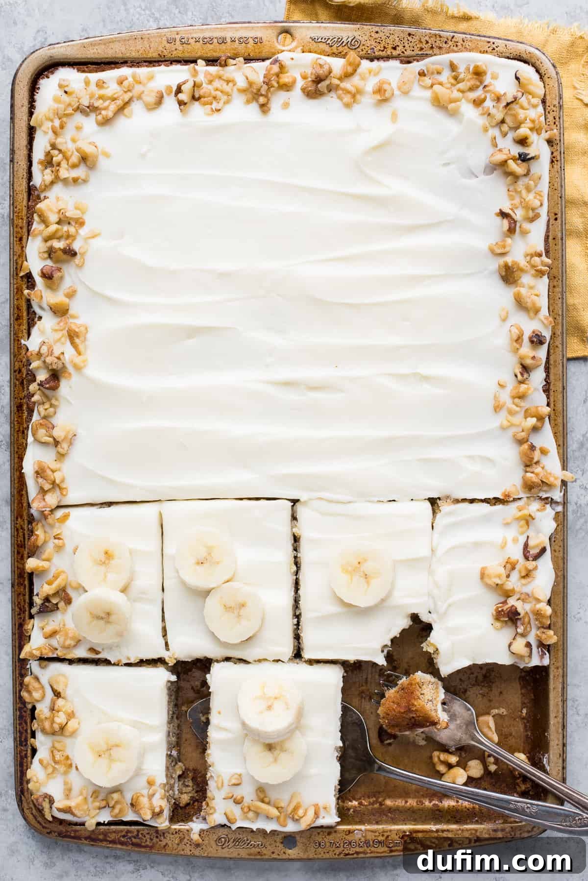 Chewy Banana Nut Bars 2 Delicious banana bars with cream cheese frosting and chopped walnuts in a sheet pan, ready to be served.