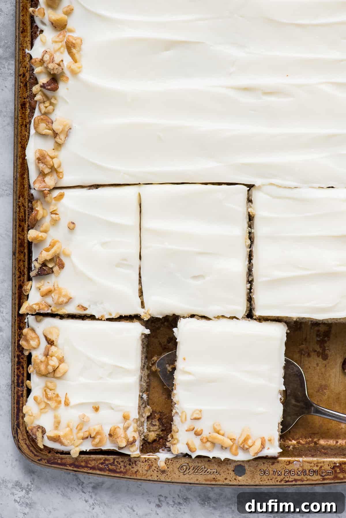 Chewy Banana Nut Bars 7 A close-up shot of a pan of banana bars topped with cream cheese frosting and a scattering of walnuts.