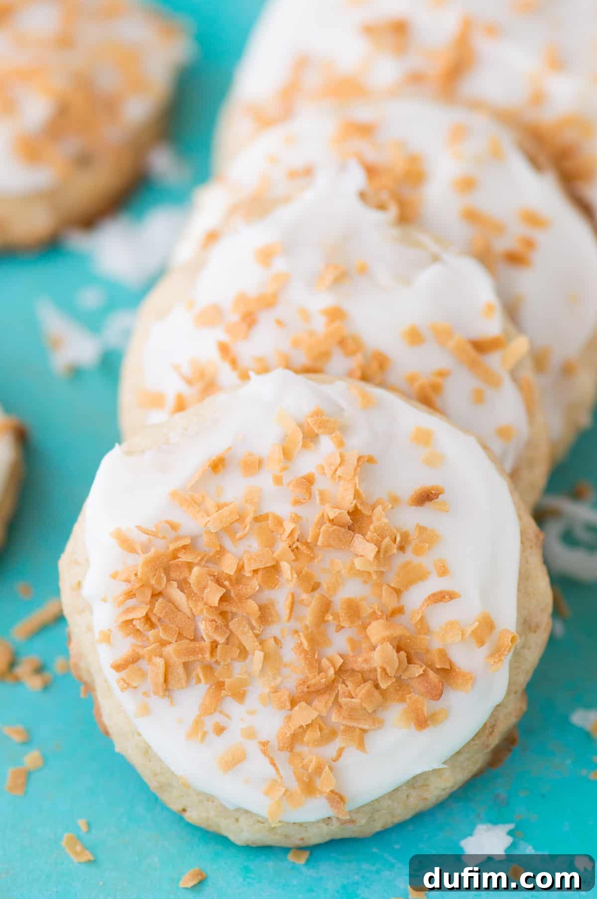 Soft and pillowy coconut cookies with white frosting on a teal background
