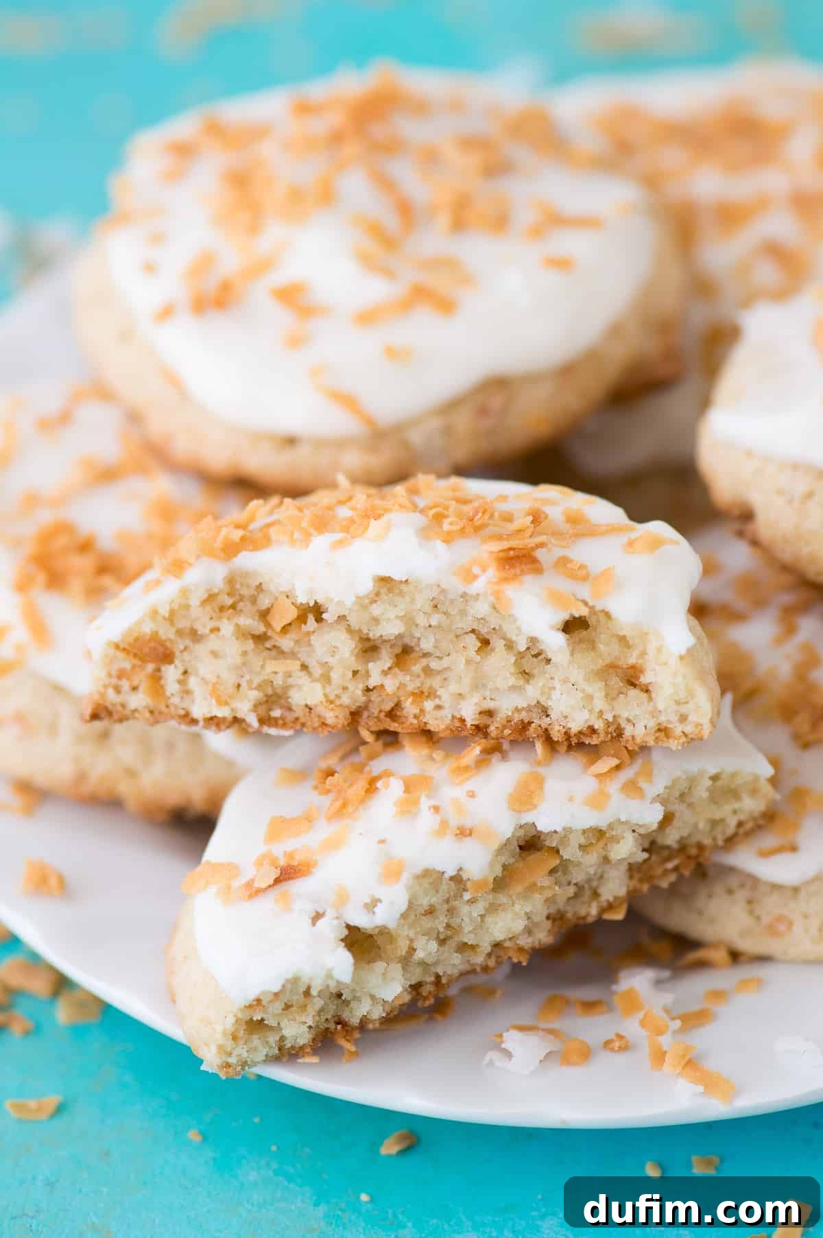Coconut cookies with white frosting on a white plate on teal background