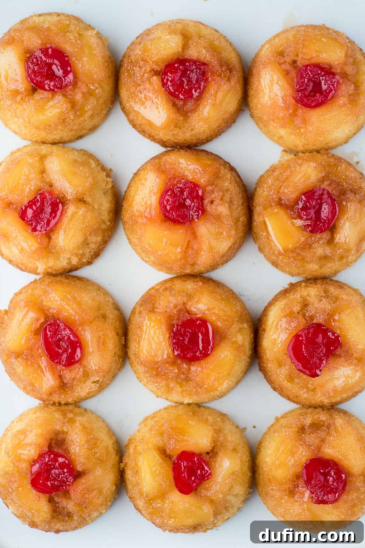 Mini pineapple upside down cakes in a grid pattern on white background, highlighting their individual charm.