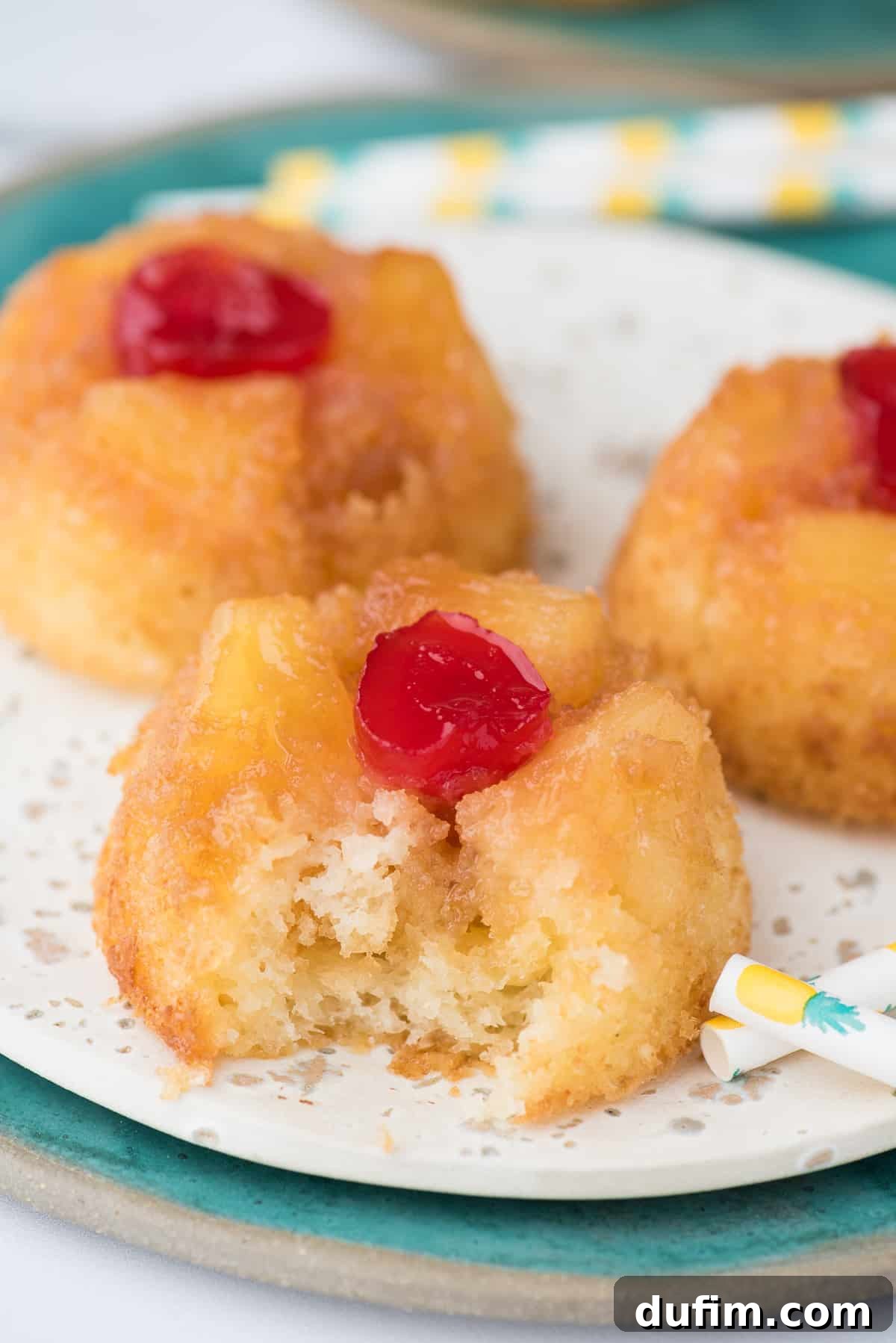 Mini pineapple upside down cupcakes on white plate, perfect for individual servings.