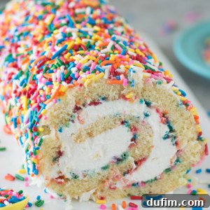 The Ultimate Funfetti Cake Roll with a vanilla cake and cream cheese frosting, adorned with many sprinkles.