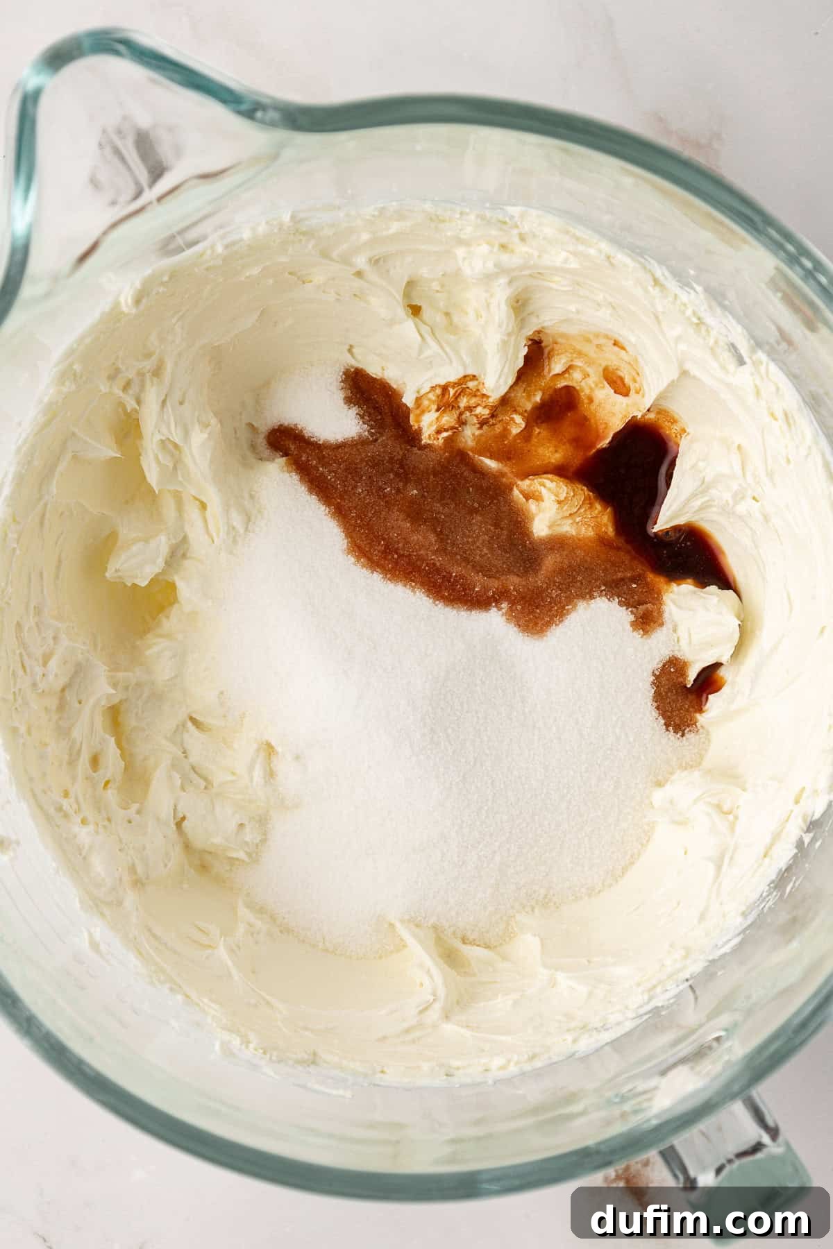 Vanilla extract being added to the cheesecake batter, enhancing its aroma and flavor.