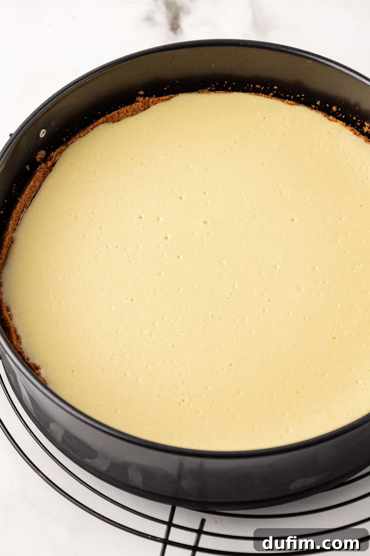 The springform pan filled with cheesecake batter, ready for the water bath and baking process.