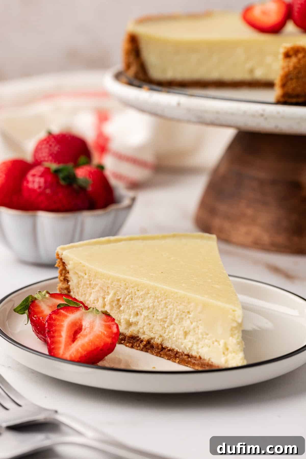 A perfectly portioned slice of classic cheesecake gracefully placed on a white plate, highlighting its smooth texture and elegant simplicity.
