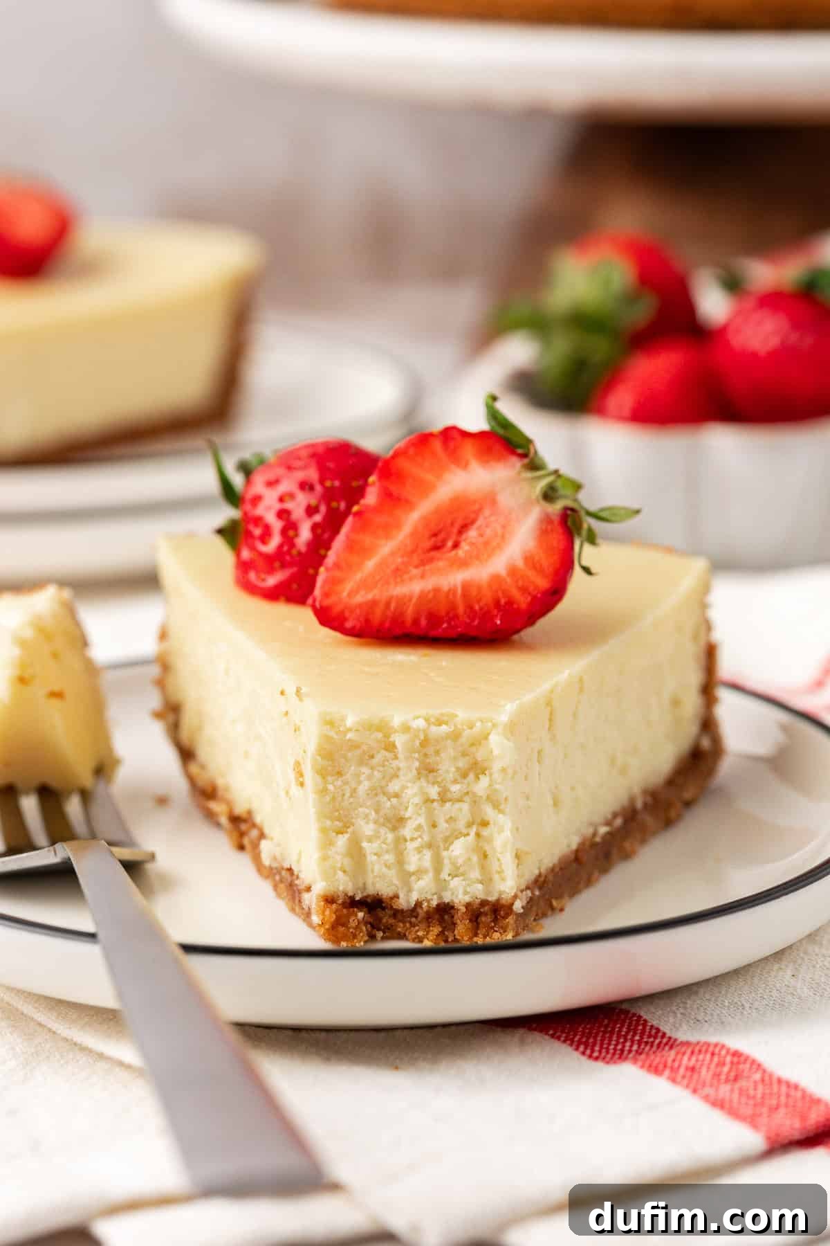 A delectable slice of classic cheesecake presented on a plate, with a small bite taken to reveal its creamy interior and perfect crust.