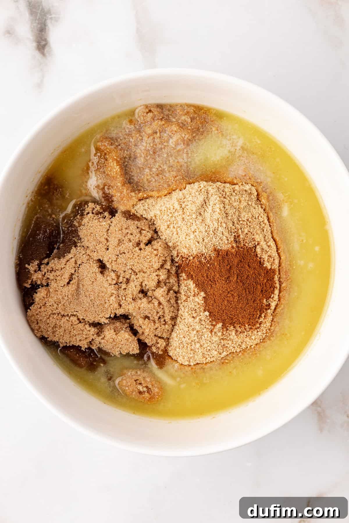 Graham cracker crumbs, brown sugar, cinnamon, and melted butter are mixed in a bowl, showing the initial steps for the cheesecake crust.