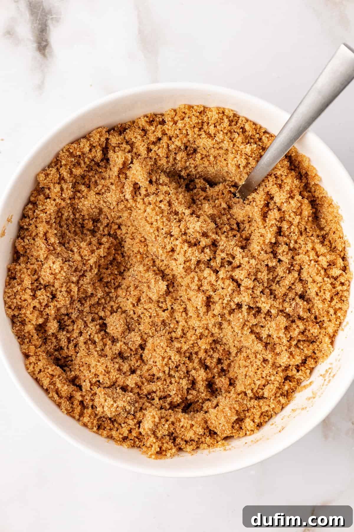 The graham cracker crust mixture, perfectly moistened and ready for pressing into the springform pan.