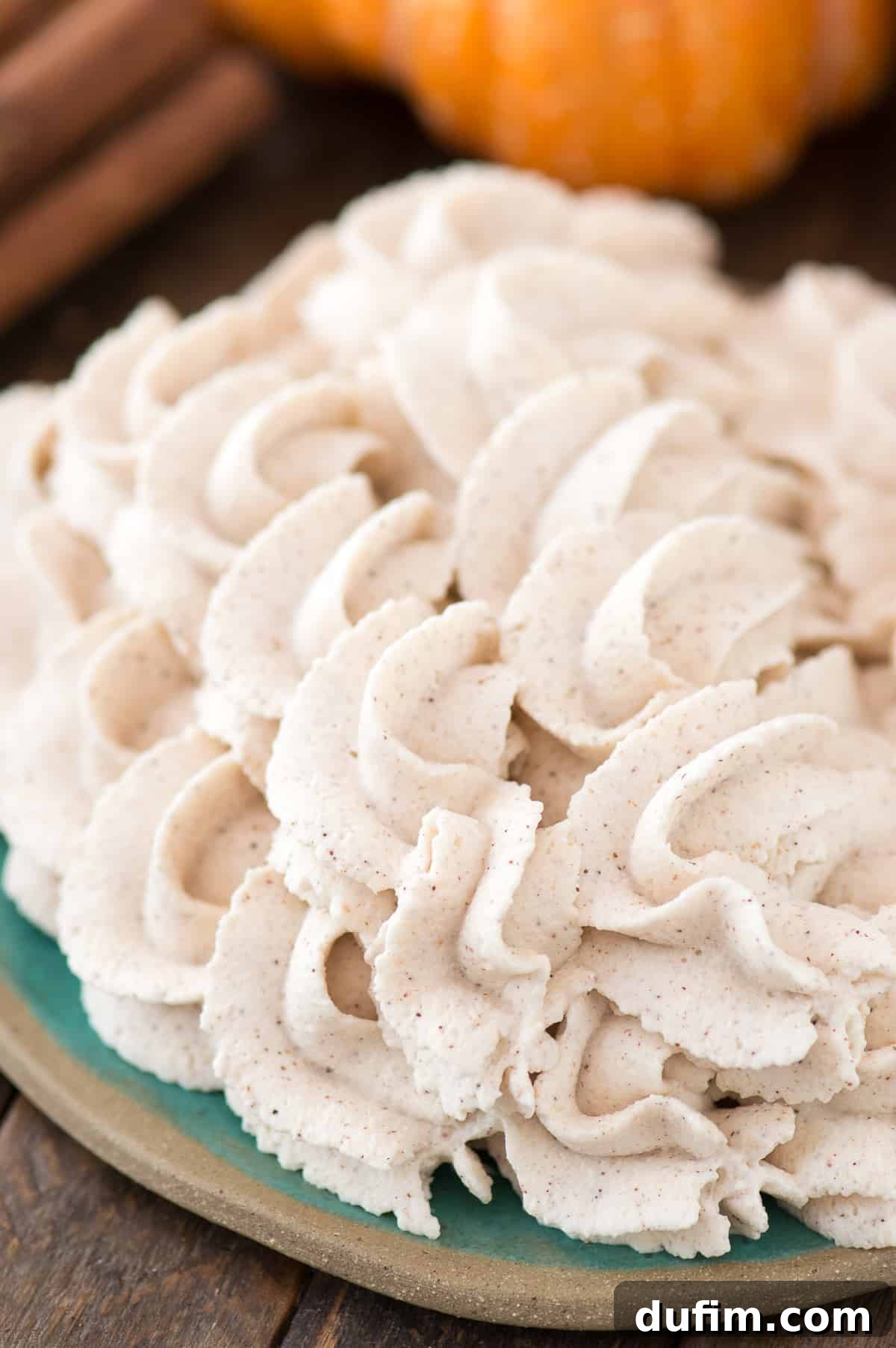 Rich pumpkin whipped cream artistically piped into elegant swirls on a vibrant teal plate, ready to be served.