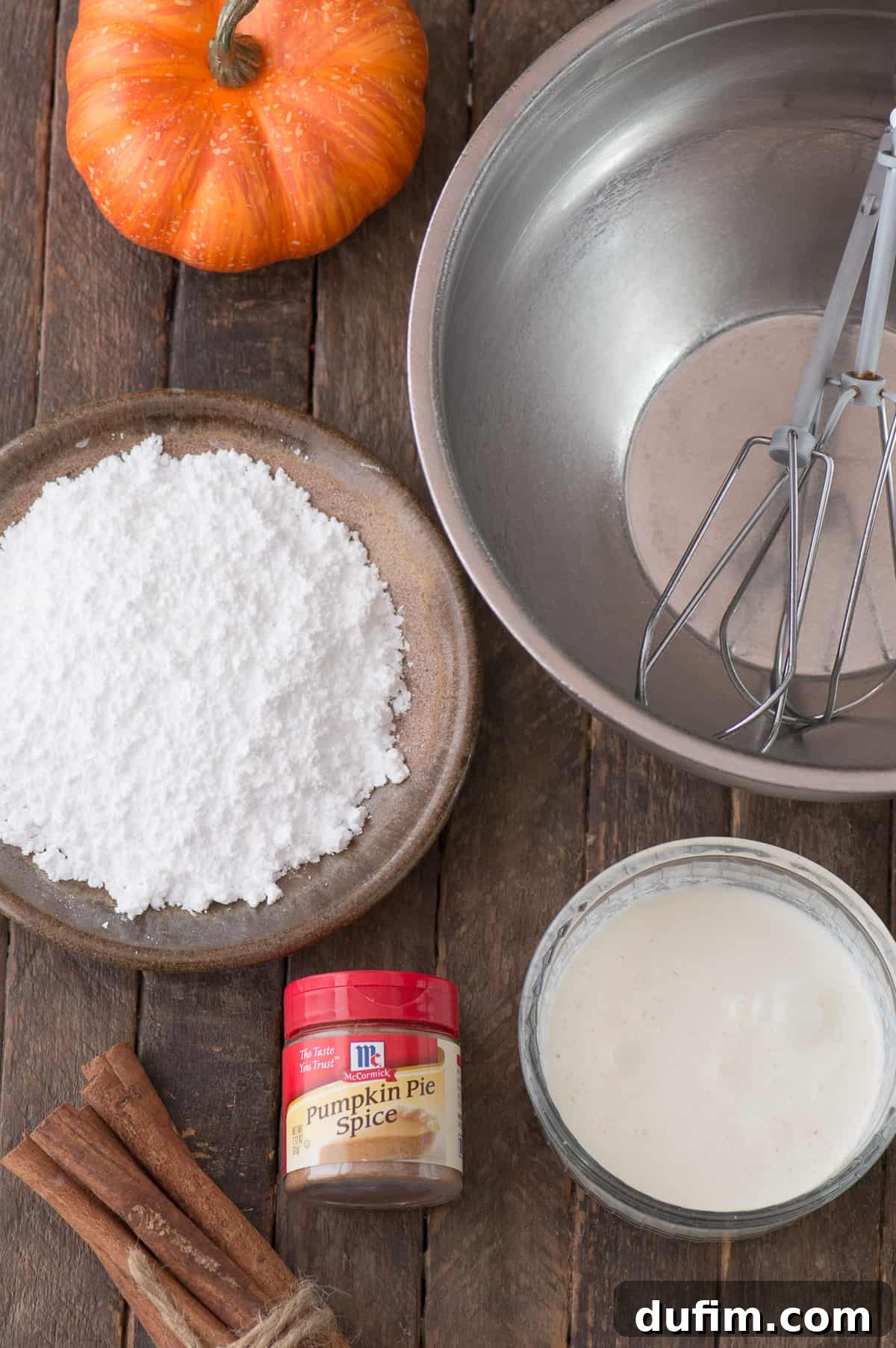 The three core ingredients for homemade pumpkin whipped cream: heavy whipping cream, powdered sugar, and pumpkin pie spice, neatly arranged.