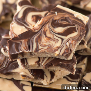 A close-up of stacked chocolate bark pieces with a marbled pattern of dark, milk, and white chocolate swirled together, reminiscent of classic tiger butter.