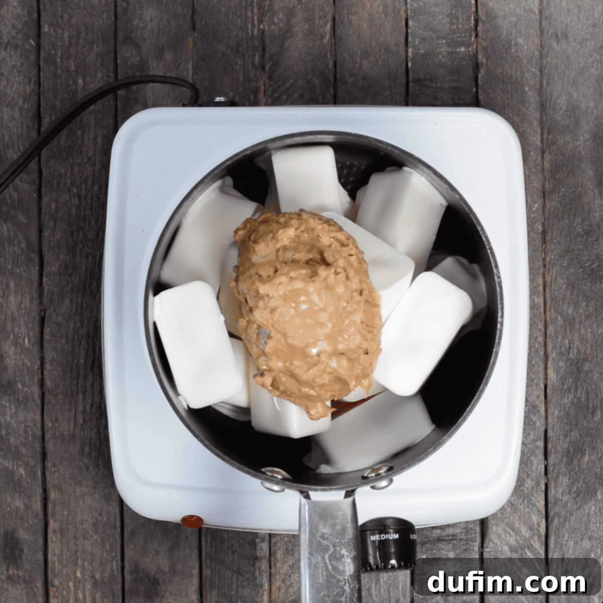 Vanilla almond bark and chunky peanut butter melting together in a pot on the stovetop.