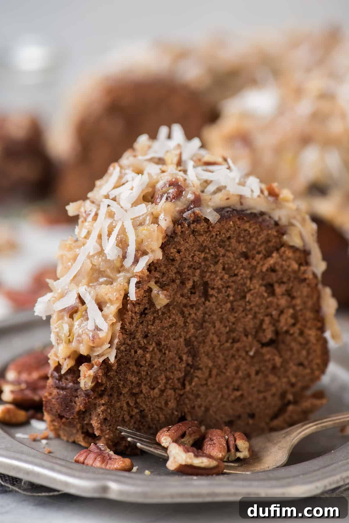 A beautifully rich and chocolatey German Chocolate Bundt Cake, generously drizzled with classic coconut pecan frosting and garnished with extra pecans. The image evokes a sense of homemade comfort and decadent flavor.
