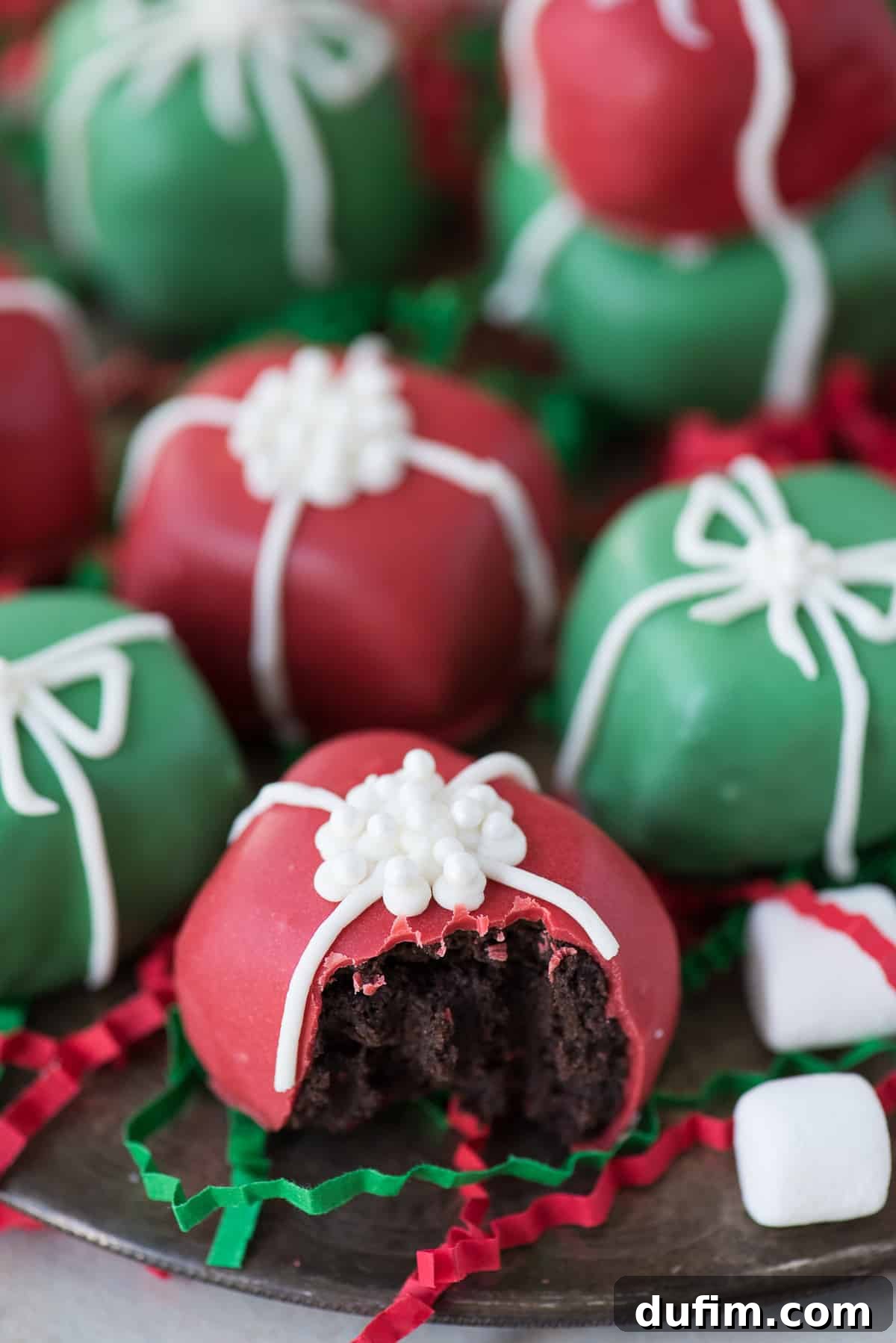 A festive close-up of Christmas present Oreo balls, featuring a mix of red and green coated treats with white piped bows, on a silver plate, ready to be enjoyed.