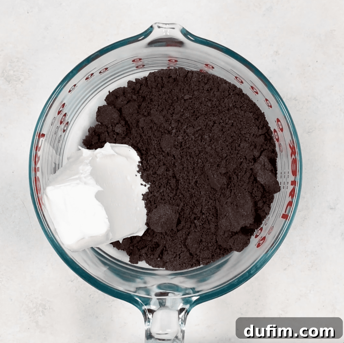 Finely crushed Oreo crumbs in a glass mixing bowl, ready to be combined with cream cheese.