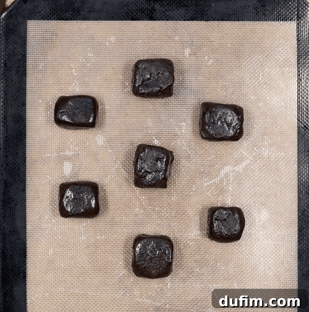 Oreo balls meticulously shaped into squares and neatly arranged on a baking sheet, ready for chilling.