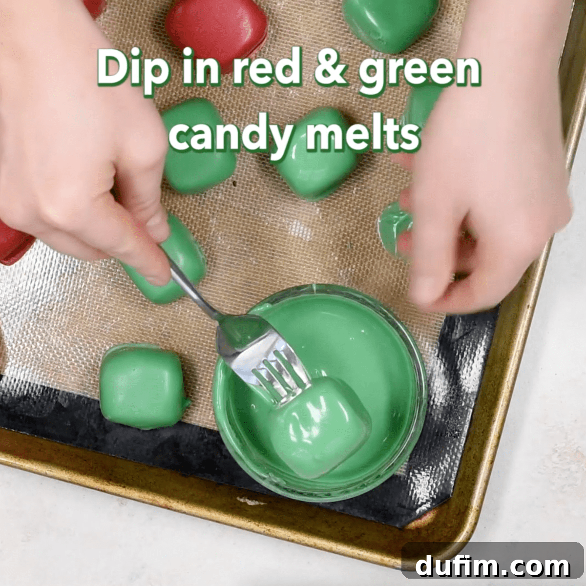 A square-shaped Oreo ball being carefully dipped into vibrant green melted candy coating, ensuring full coverage.