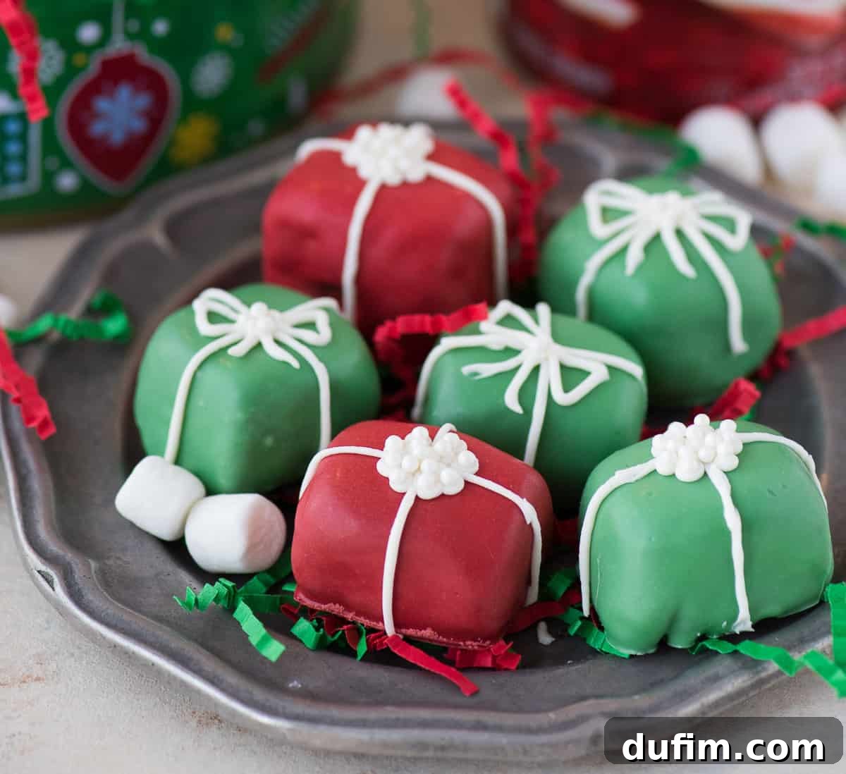 A stunning arrangement of red and green Christmas present Oreo balls, decorated with elegant white bows, on a reflective metal plate.