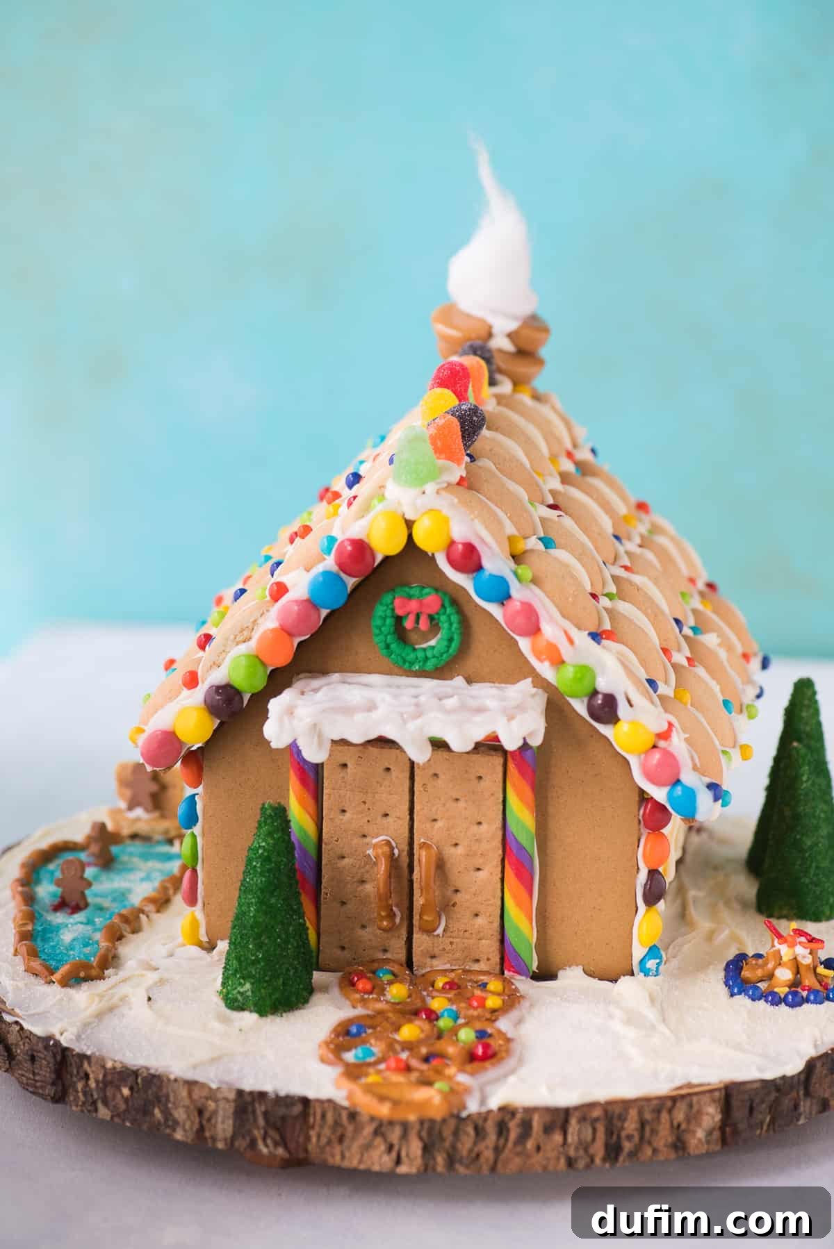 A beautifully decorated gingerbread house with various candies, an ice skating rink, and a marshmallow snowman.