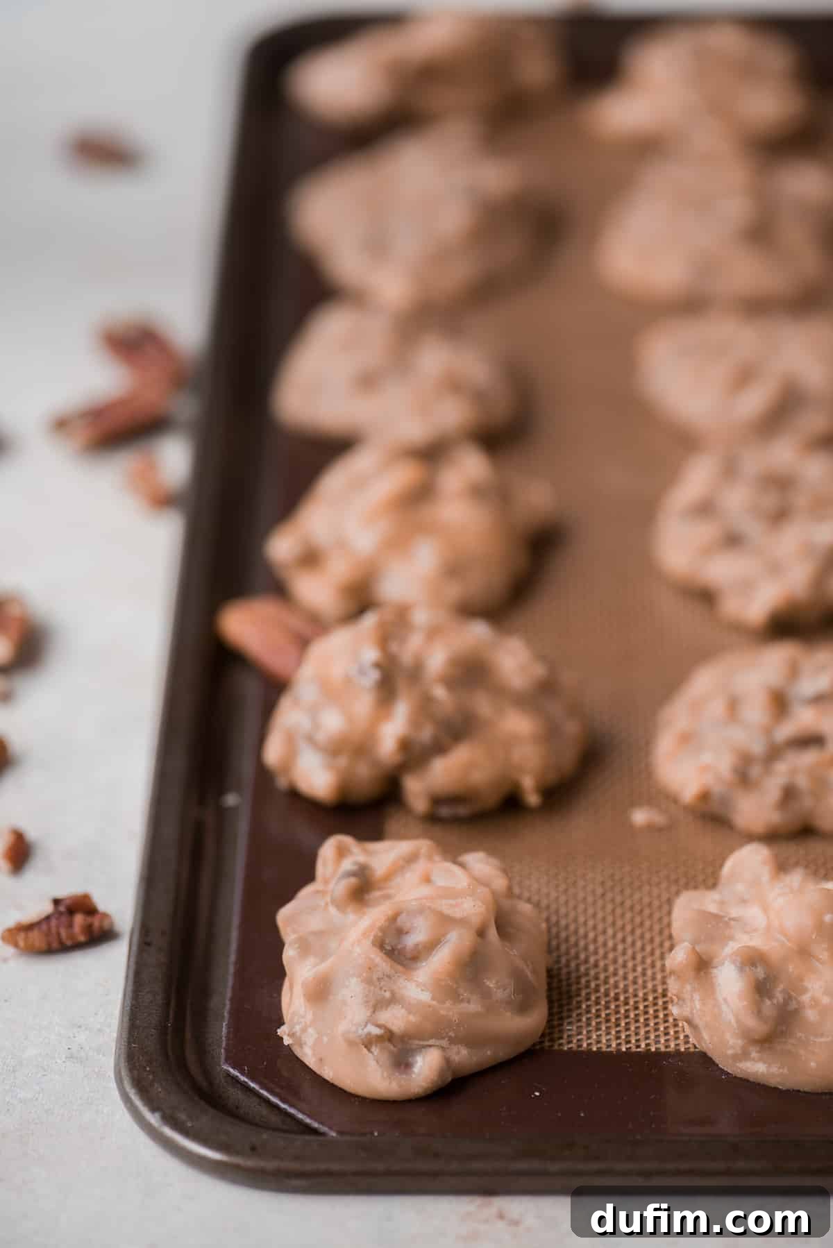 pecan pralines arranged in a grid on baking sheet