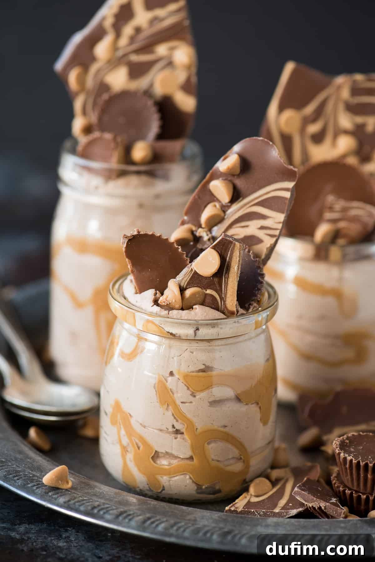 Close-up of a chocolate peanut butter mousse jar, showing the creamy texture and layers, with spoons ready for tasting.
