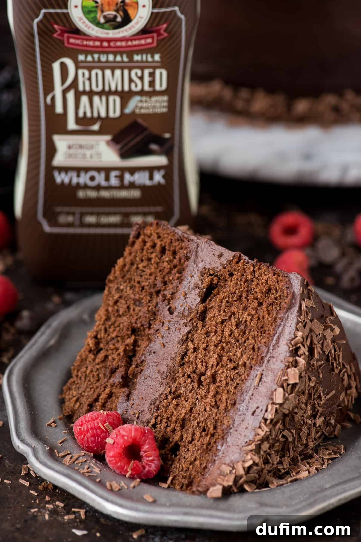 A two-layer chocolate velvet cake, fully frosted and decorated with fresh berries and chocolate shavings, ready to be sliced and served.