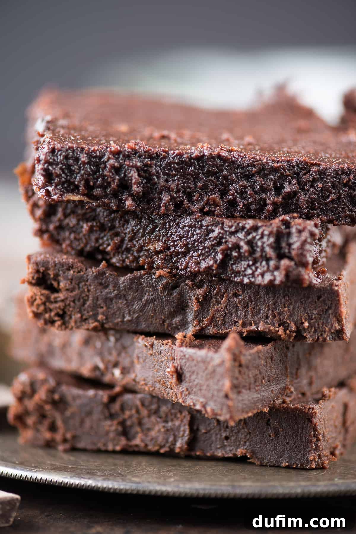 Five homemade fudgy brownies arranged neatly on a baking sheet, fresh out of the oven.