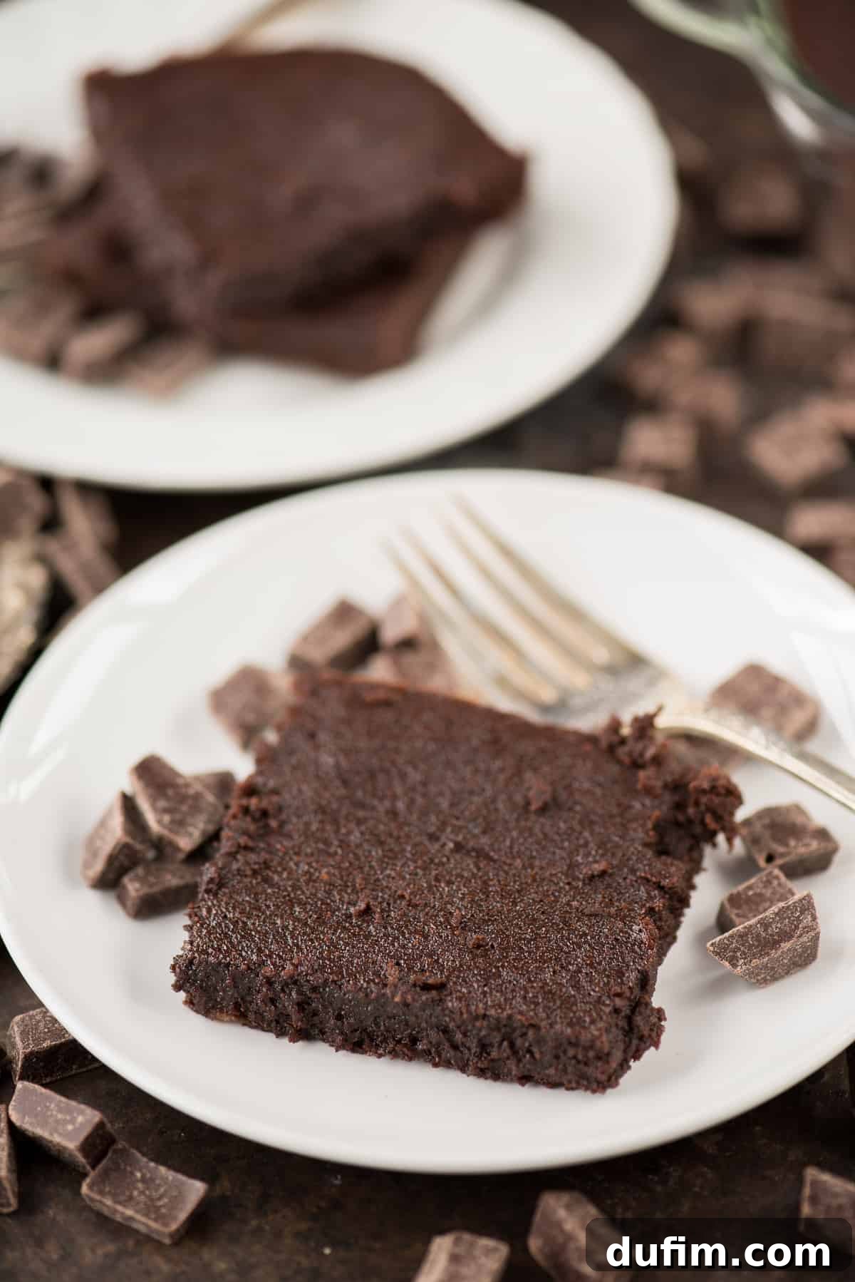 One healthier fudgy brownie with small chocolate pieces and a silver fork on a white plate, ready to be enjoyed.