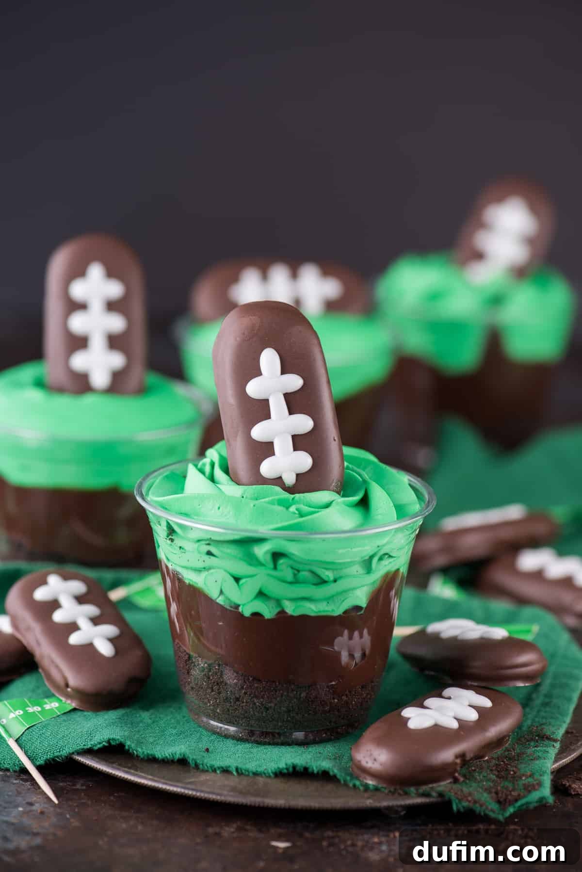 Football themed dirt cups - a fun football dessert to make for game day, super bowl, or a football themed birthday party! We made these and substituted football sprinkles for the football cookie on top.