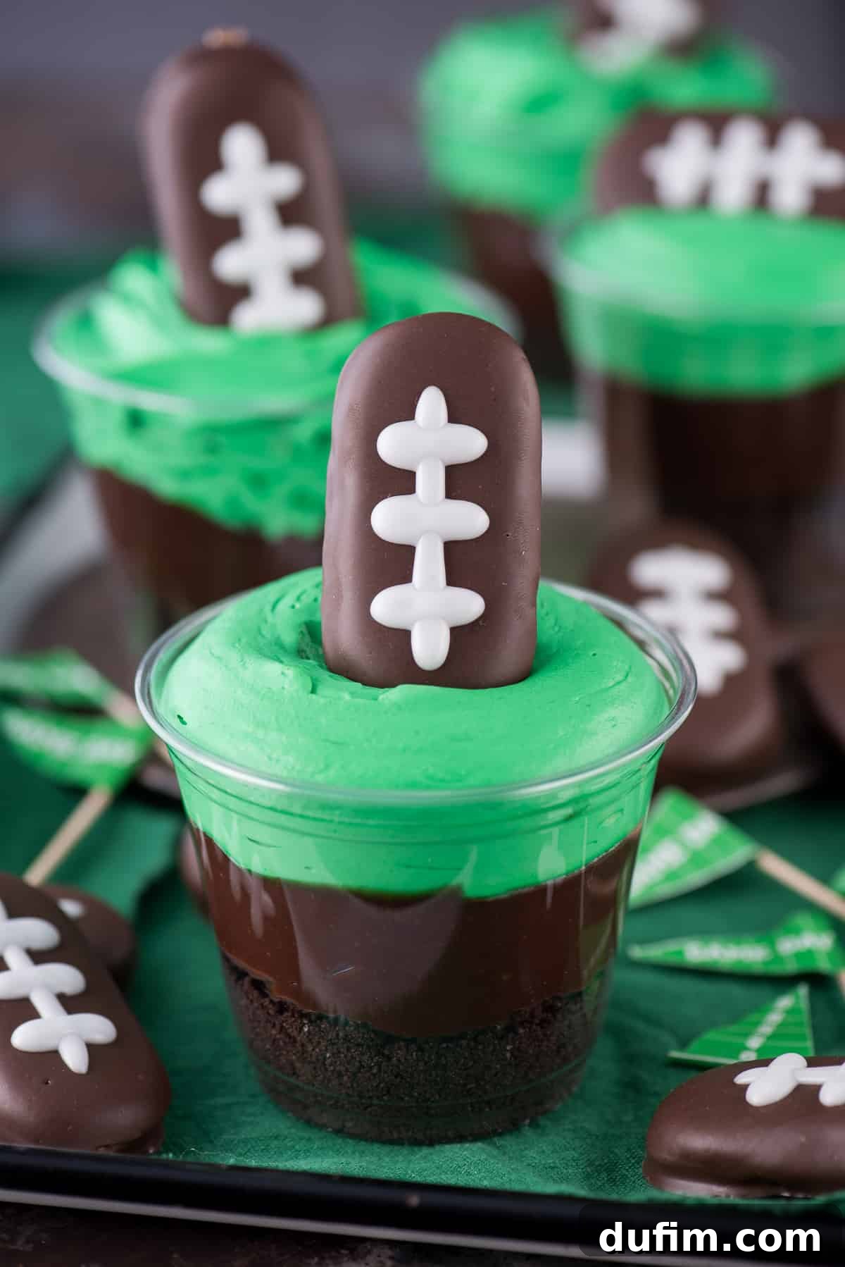 Football themed dirt cups - a fun football dessert to make for game day, super bowl, or a football themed birthday party! We made these and substituted football sprinkles for the football cookie on top.
